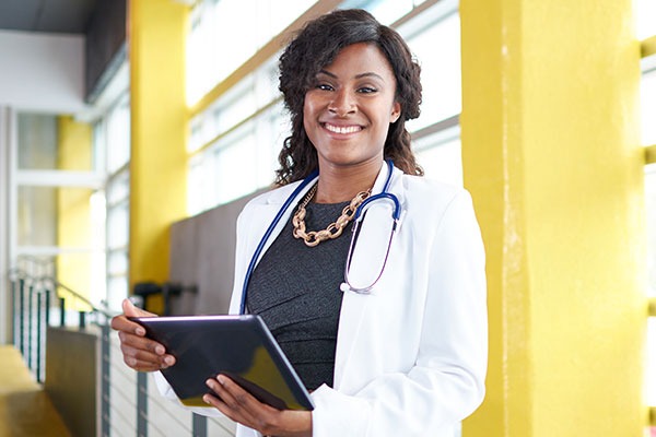 Smiling doctor in lab coat, holding a tablet